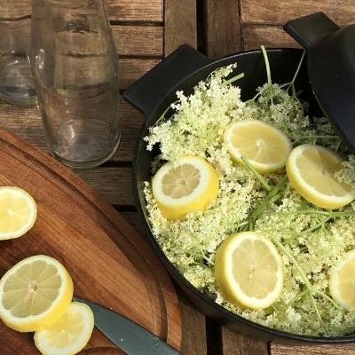 Elderflowers and lemons in dutch oven, and sliced lemons on a cutting board