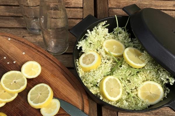 Elderflowers and lemons in dutch oven, and sliced lemons on a cutting board